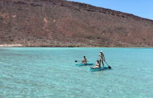 People paddleboard through turquoise water at Balandra beach.